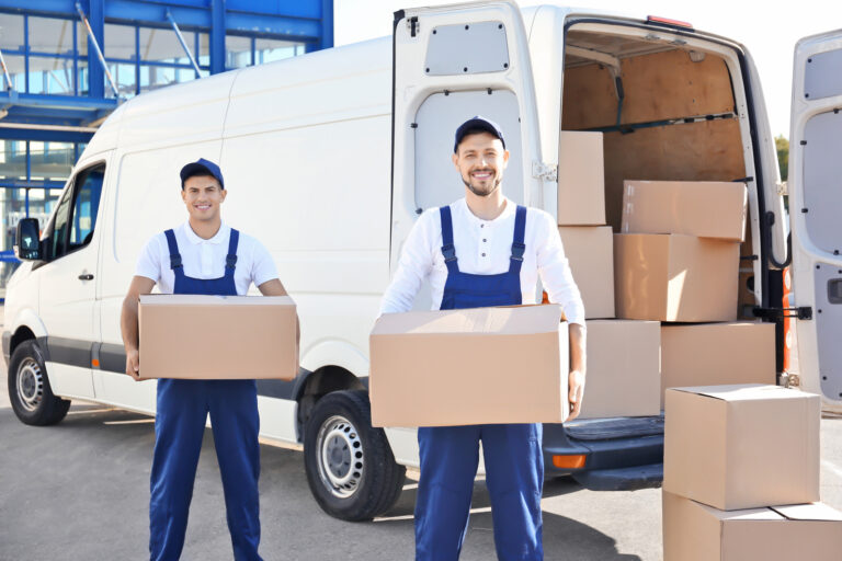 Delivery men with moving boxes near car