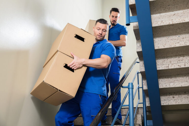 Two Movers Carrying Cardboard Boxes On Staircase
