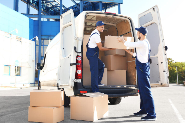 Delivery men unloading moving boxes from car