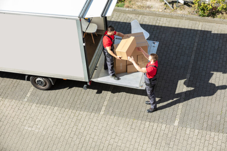 Male Movers Unloading The Cardboard Boxes Form Truck