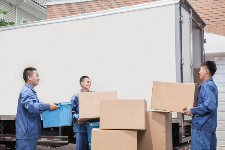 Movers unloading a moving van, many stacked cardboard boxes