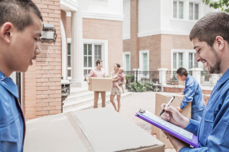 Mover holding clipboard and invoice, family in the background