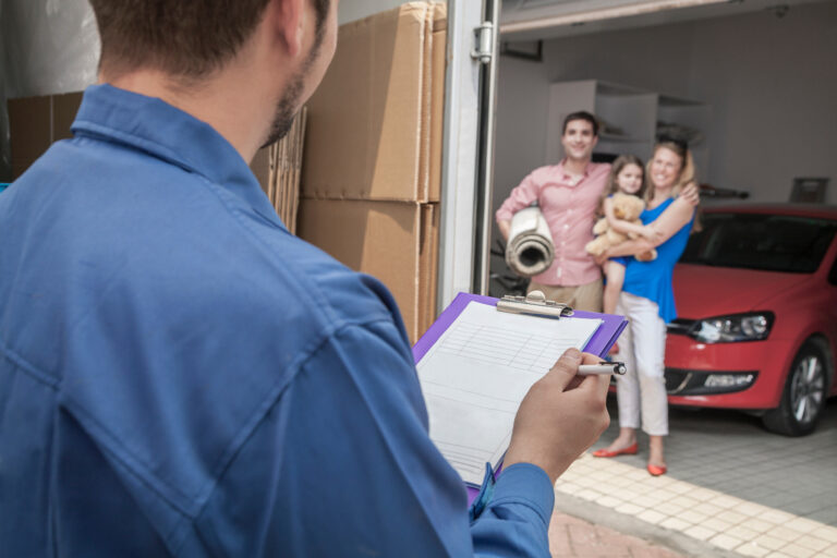 Mover holding clipboard and invoice, family in the background