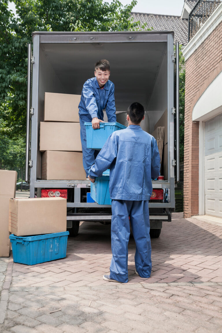 Movers unloading a moving van, passing a cardboard box
